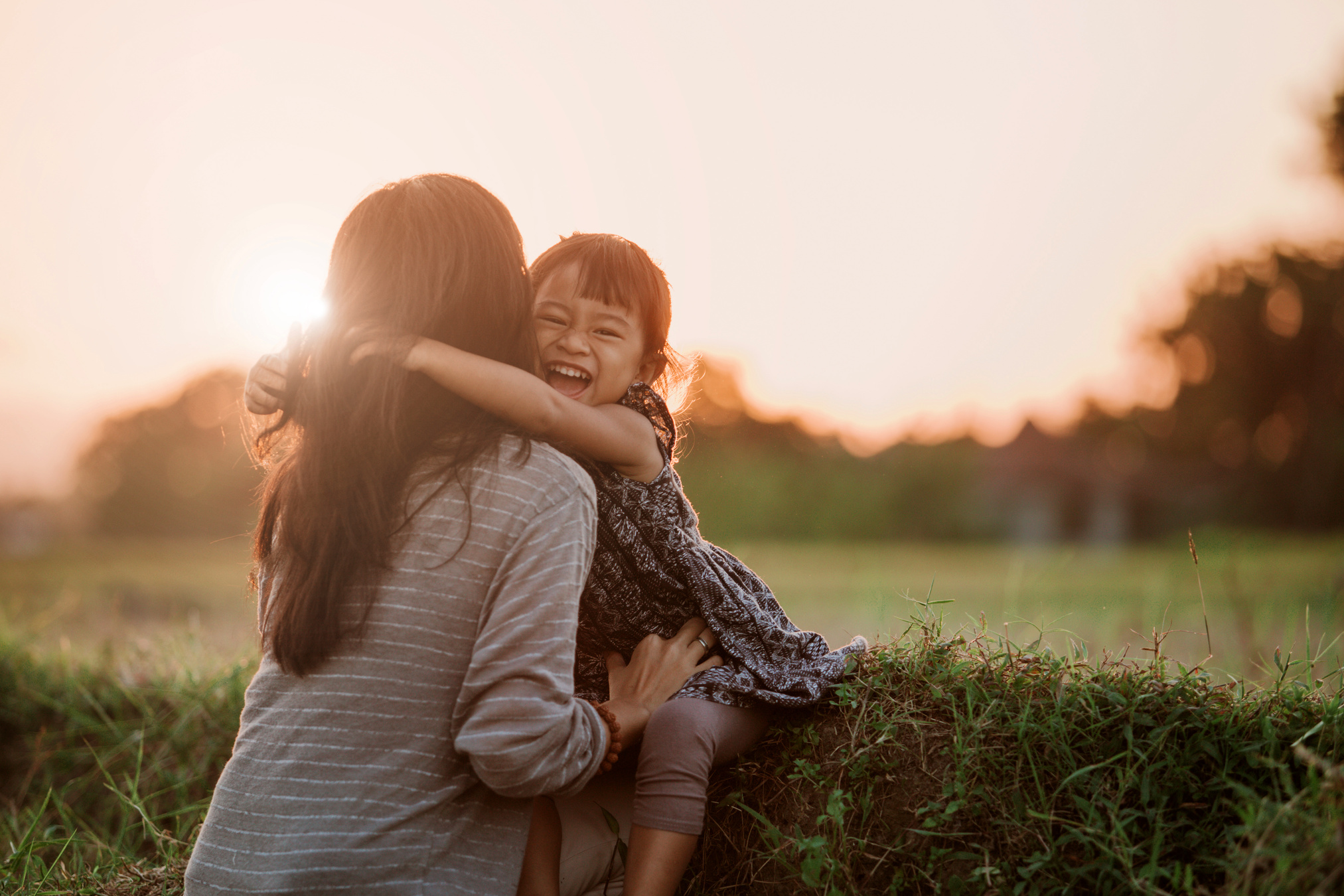 Mom and Kid Hugging under the Sunset Sky